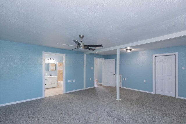 unfurnished bedroom featuring ensuite bathroom, ceiling fan, a textured ceiling, and light colored carpet