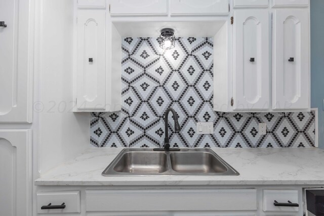 kitchen with white cabinetry, sink, and backsplash