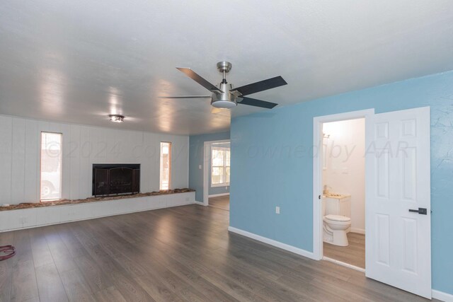 unfurnished living room with dark hardwood / wood-style flooring and ceiling fan