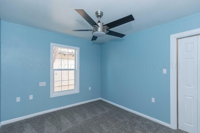 empty room with ceiling fan and dark carpet