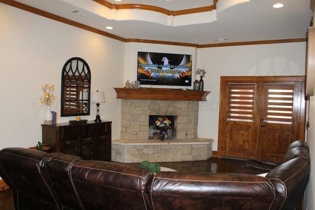 living area featuring a stone fireplace, a tray ceiling, ornamental molding, visible vents, and recessed lighting