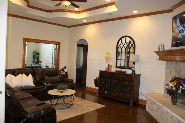 living room featuring a tray ceiling, arched walkways, recessed lighting, ceiling fan, and crown molding
