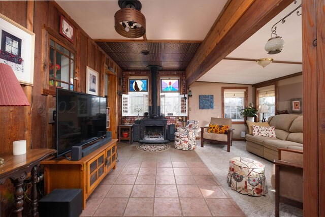 tiled living room with beamed ceiling, wooden walls, and a wood stove