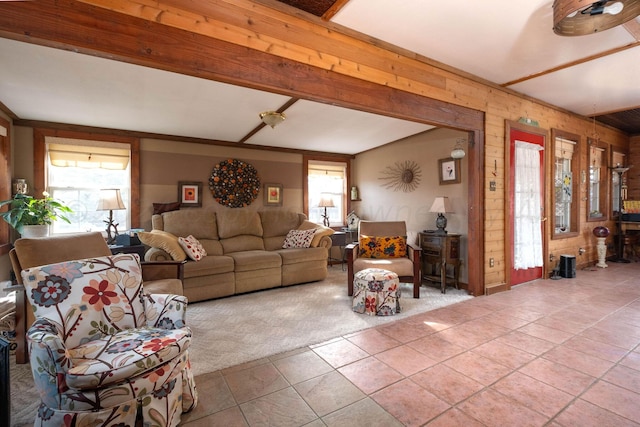 living room featuring a wealth of natural light, wooden walls, light tile patterned flooring, and beam ceiling