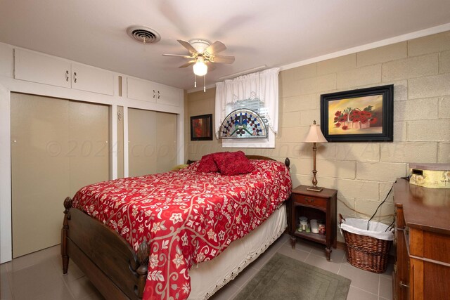 bedroom featuring light tile patterned floors, ceiling fan, and two closets