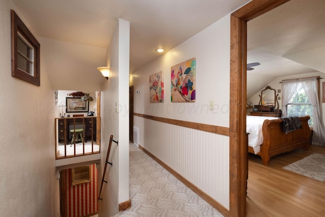 hall featuring light wood-type flooring and vaulted ceiling