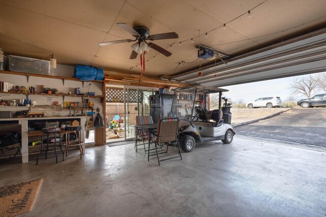 garage with a workshop area, black fridge, ceiling fan, and a garage door opener