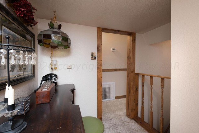 hall featuring carpet flooring and a textured ceiling