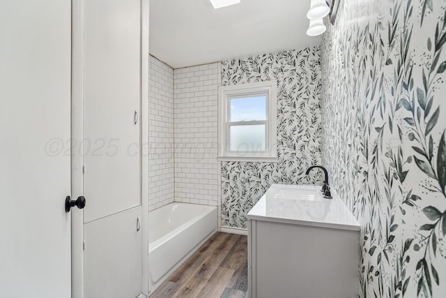 517 Whittier St, Hereford, TX 79045 - full bath featuring wallpapered walls, wood finished floors, vanity, and washtub / shower combination