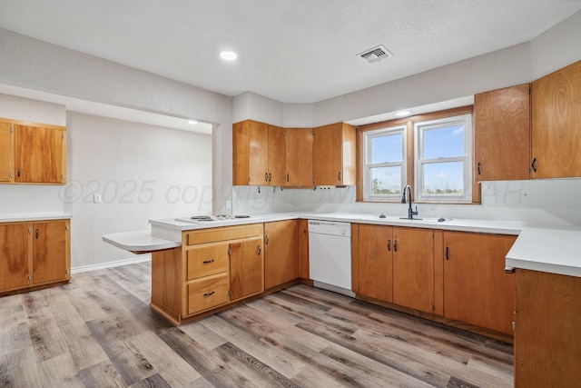 517 Whittier St, Hereford, TX 79045 - kitchen featuring white dishwasher, a peninsula, light wood-style flooring, light countertops, and brown cabinets