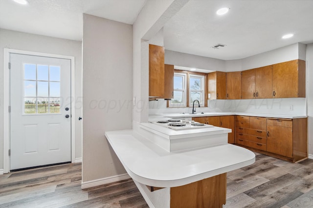 517 Whittier St, Hereford, TX 79045 - kitchen with brown cabinets, light countertops, a peninsula, white electric cooktop, and light wood-style floors