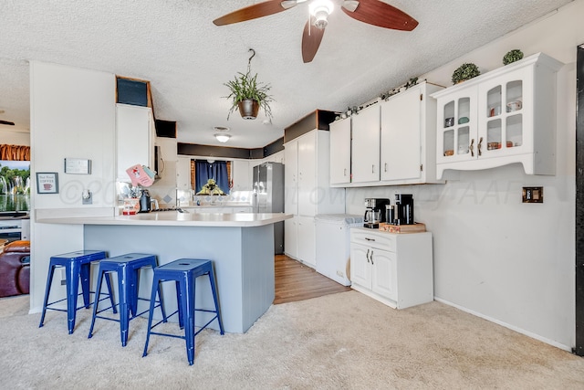 kitchen featuring a peninsula, a breakfast bar, a textured ceiling, and ceiling fan