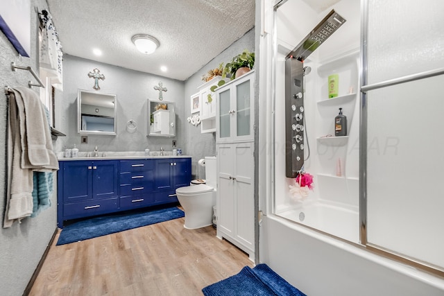 bathroom featuring a textured ceiling, wood finished floors, shower / bathing tub combination, double vanity, and toilet