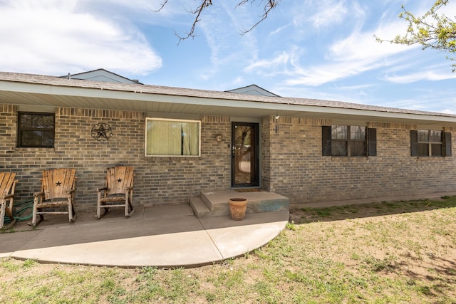 view of front of property with brick siding and a patio area