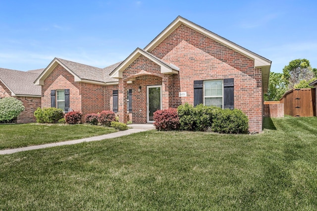 ranch-style home featuring brick siding, a shingled roof, and a front yard