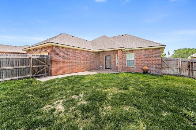 back of house with brick siding, a fenced backyard, a yard, and a patio