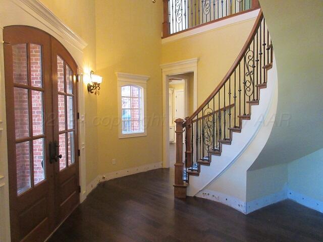 foyer entrance featuring a towering ceiling, dark hardwood / wood-style floors, and french doors