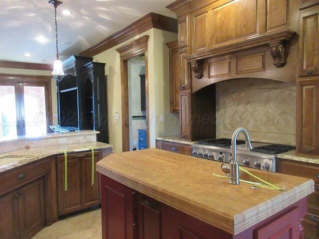 kitchen featuring pendant lighting, a kitchen island, crown molding, and wood counters