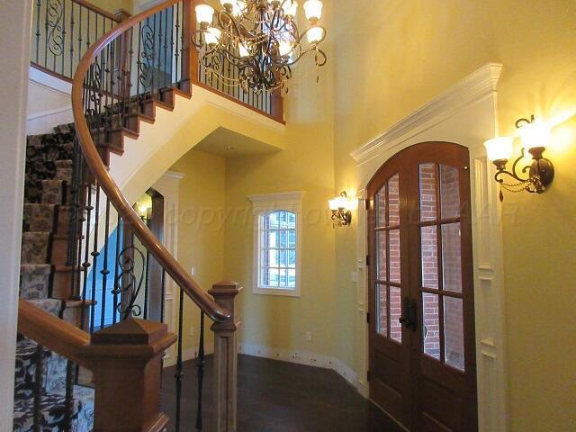 foyer entrance with an inviting chandelier, a towering ceiling, and french doors