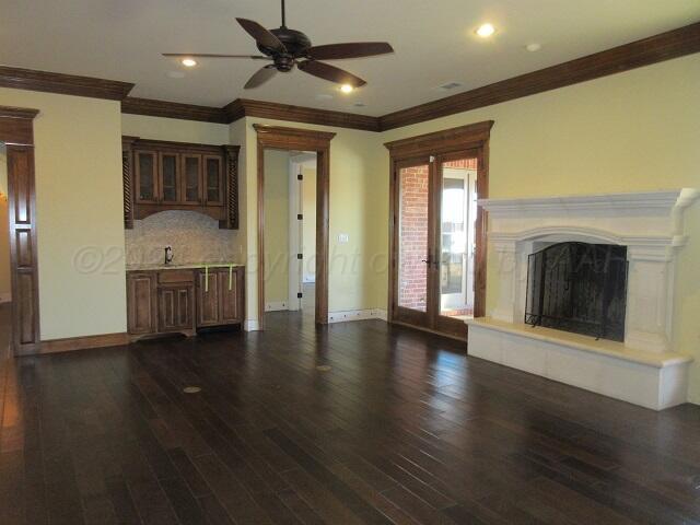 unfurnished living room with ceiling fan, dark wood-type flooring, sink, and ornamental molding