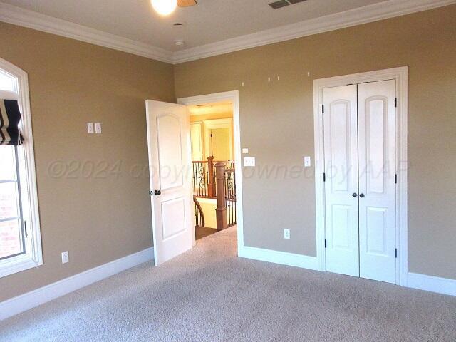 unfurnished bedroom featuring a closet, carpet, and ornamental molding