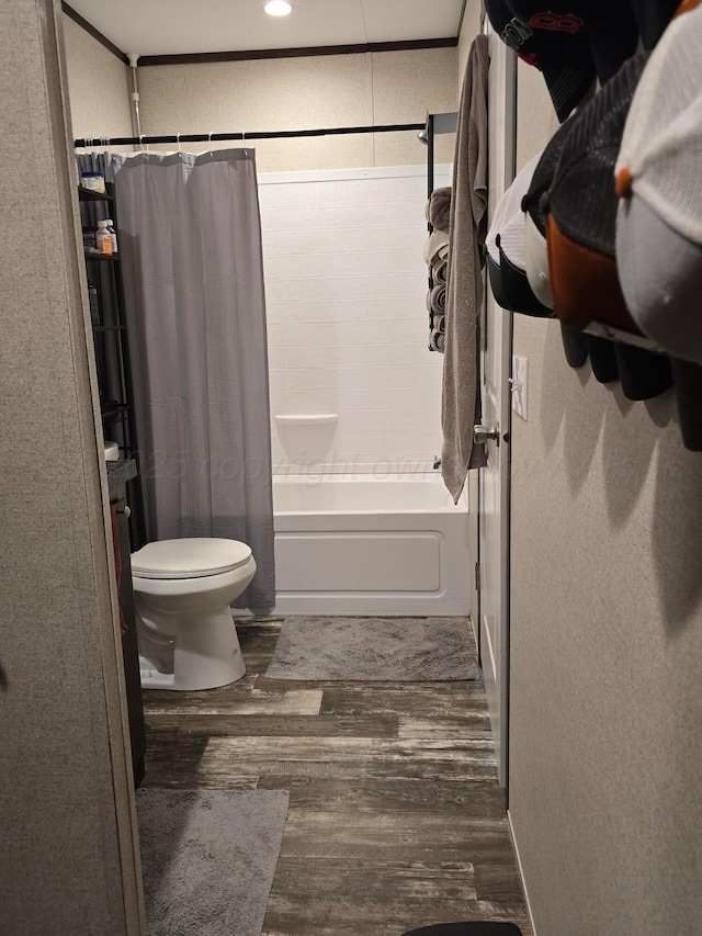 bathroom featuring shower / bathtub combination with curtain, hardwood / wood-style flooring, crown molding, and toilet