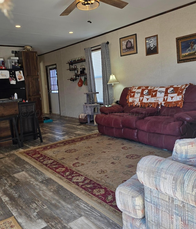 living room with ornamental molding, indoor bar, dark wood-type flooring, and ceiling fan