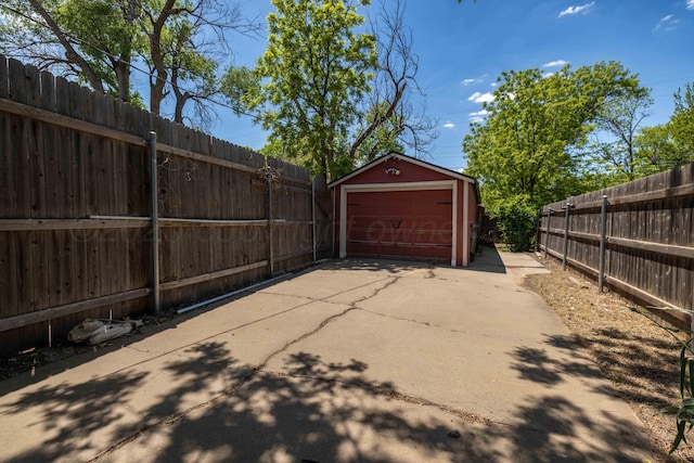 view of patio featuring a garage, an outdoor structure, and driveway