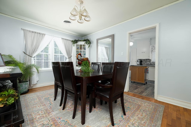 dining room featuring a chandelier, light wood-style floors, crown molding, and baseboards