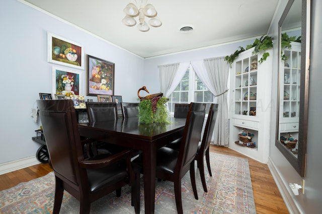 dining room with a chandelier, wood finished floors, crown molding, and baseboards