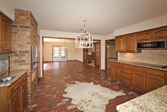 4410 Chandler Dr, Amarillo, TX 79109 - kitchen featuring appliances with stainless steel finishes, a chandelier, brick floors, and decorative backsplash