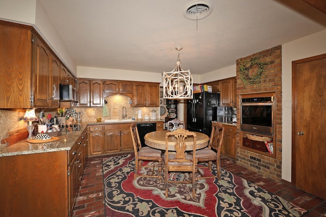 4410 Chandler Dr, Amarillo, TX 79109 - kitchen with brick flooring, black appliances, a chandelier, backsplash, and brown cabinetry