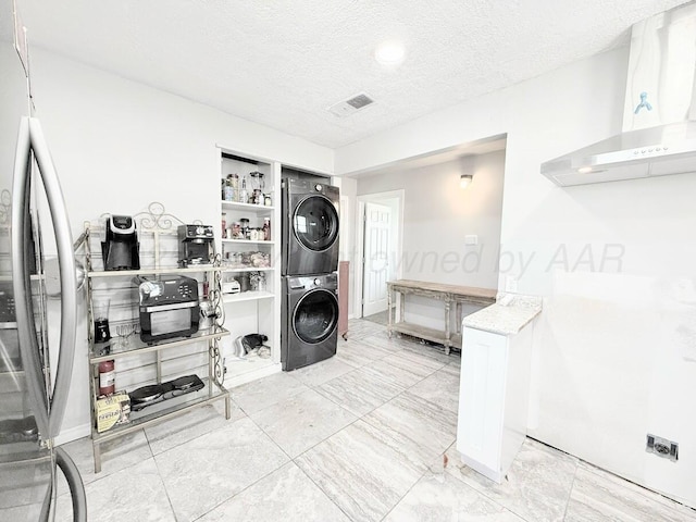 laundry area with stacked washer / drying machine and a textured ceiling