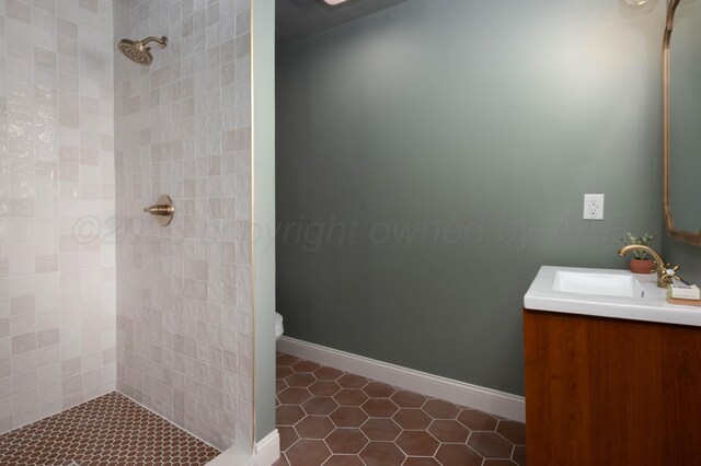 bathroom with tile patterned flooring, vanity, toilet, and a tile shower