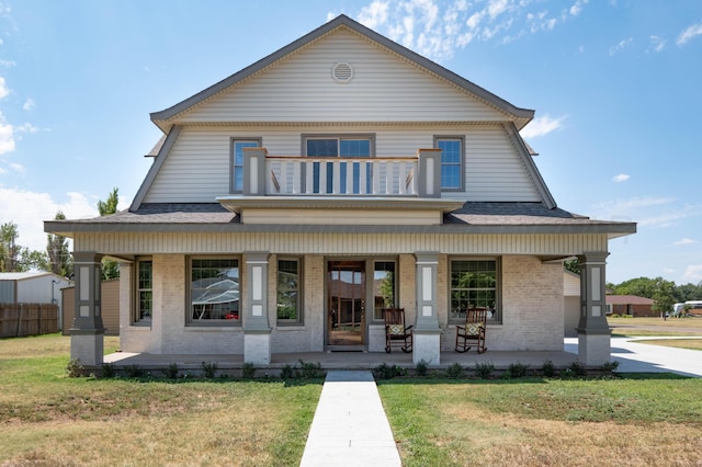 view of front facade with covered porch, a balcony, and a front lawn