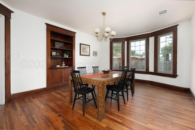 dining area featuring built in shelves, dark wood-type flooring, and a chandelier