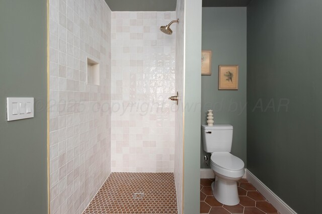 bathroom featuring tile patterned flooring, toilet, and tiled shower