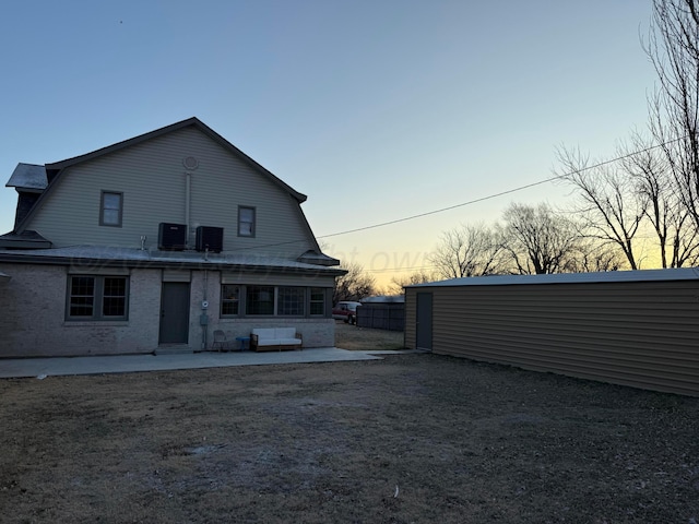 back house at dusk featuring central air condition unit and a patio area