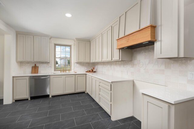 kitchen with dishwasher, tasteful backsplash, dark tile patterned flooring, and sink