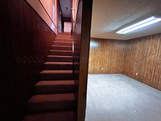 basement with wooden walls, a textured ceiling, and carpet floors