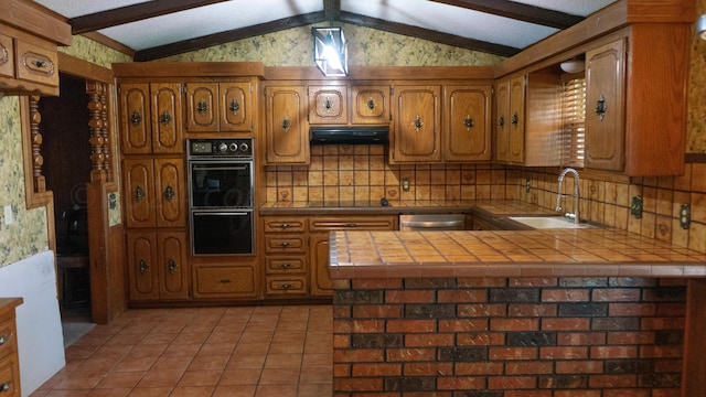 kitchen with black appliances, sink, tile counters, and lofted ceiling with beams