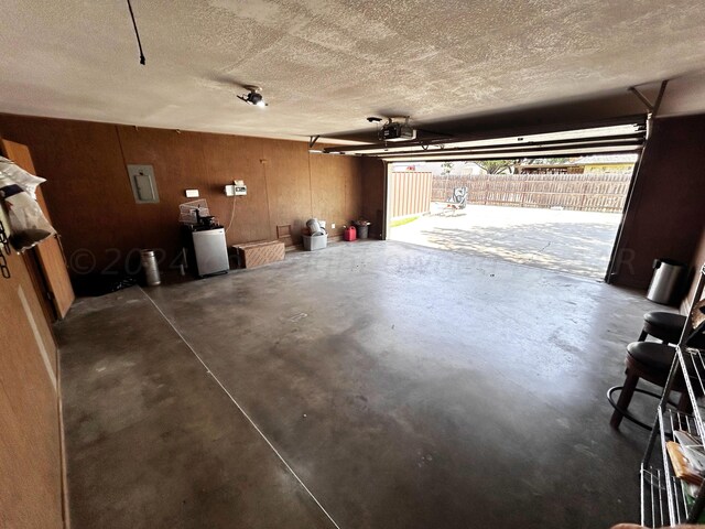 garage featuring electric panel, a garage door opener, and wooden walls