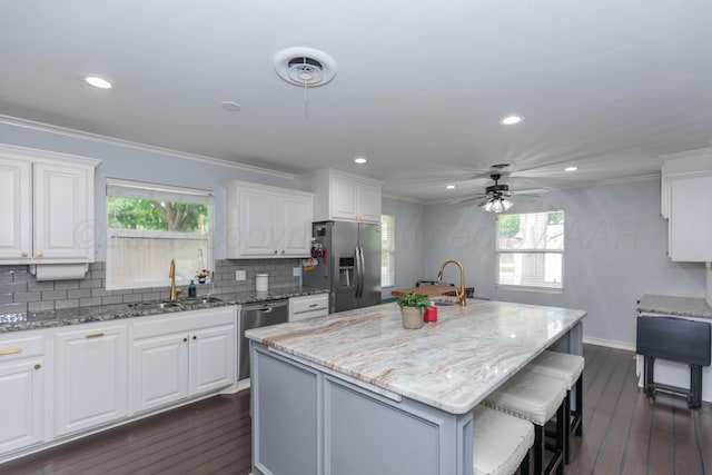 5109 Tawney Ave, Amarillo, TX 79106 - kitchen featuring stainless steel appliances, a center island with sink, a ceiling fan, backsplash, and white cabinets