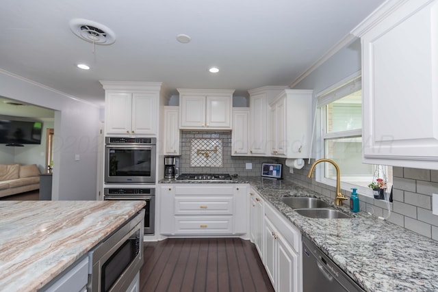 5109 Tawney Ave, Amarillo, TX 79106 - kitchen with appliances with stainless steel finishes, white cabinets, light stone countertops, backsplash, and ornamental molding