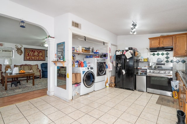 1411 N Highland St, Amarillo, TX 79107 - kitchen with separate washer and dryer, gas range, black fridge, under cabinet range hood, and tasteful backsplash