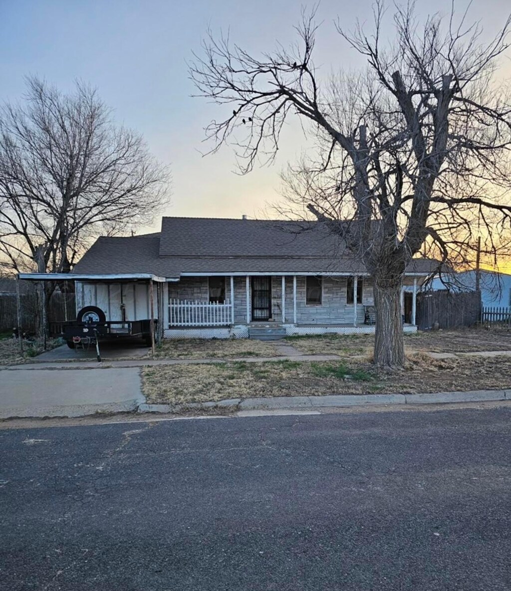 view of front facade with covered porch, concrete driveway, roof with shingles, and a carport