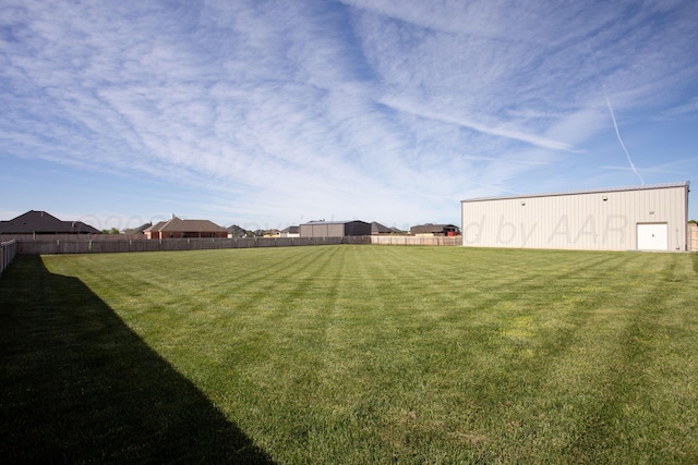 view of yard featuring fence, an outbuilding, and a pole building