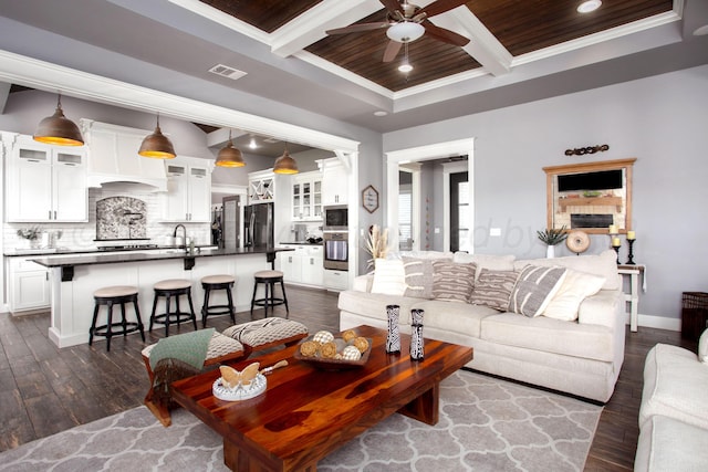 living room with visible vents, crown molding, ceiling fan, dark wood finished floors, and coffered ceiling