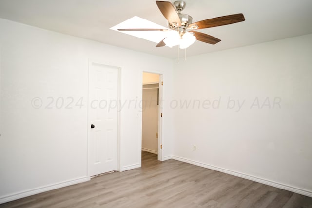 unfurnished bedroom featuring a skylight, light hardwood / wood-style floors, and ceiling fan