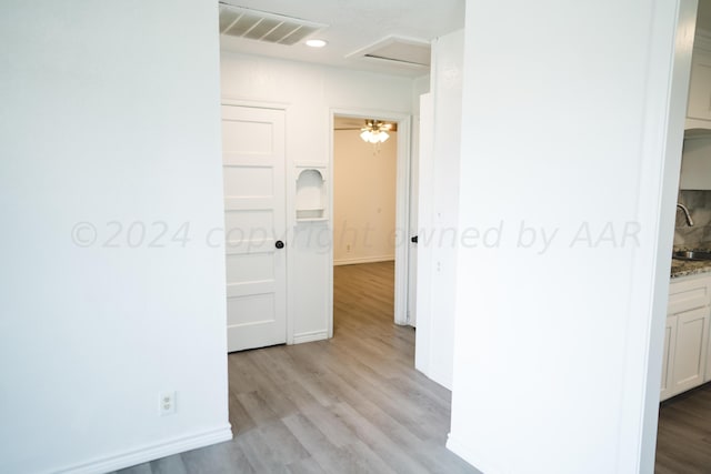 corridor with sink and light wood-type flooring